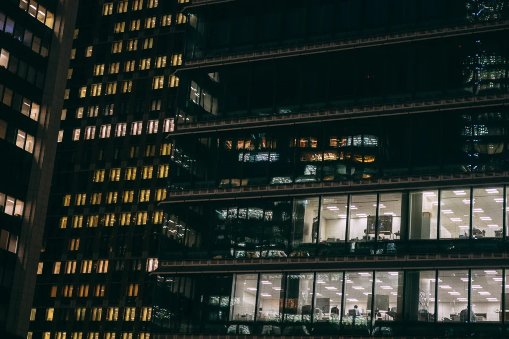残業で明かりがついている高層ビルの写真